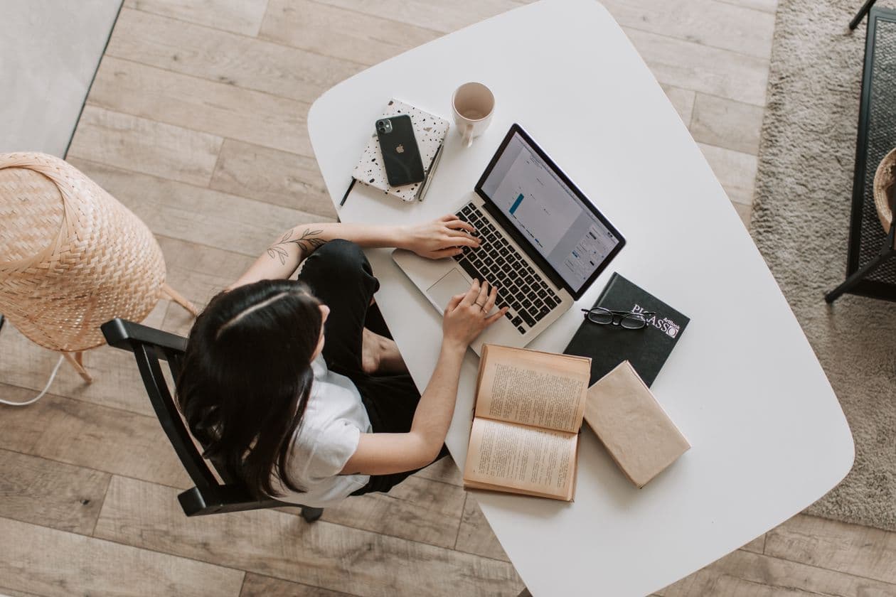 Student working on a laptop at a desk with books, seen from above