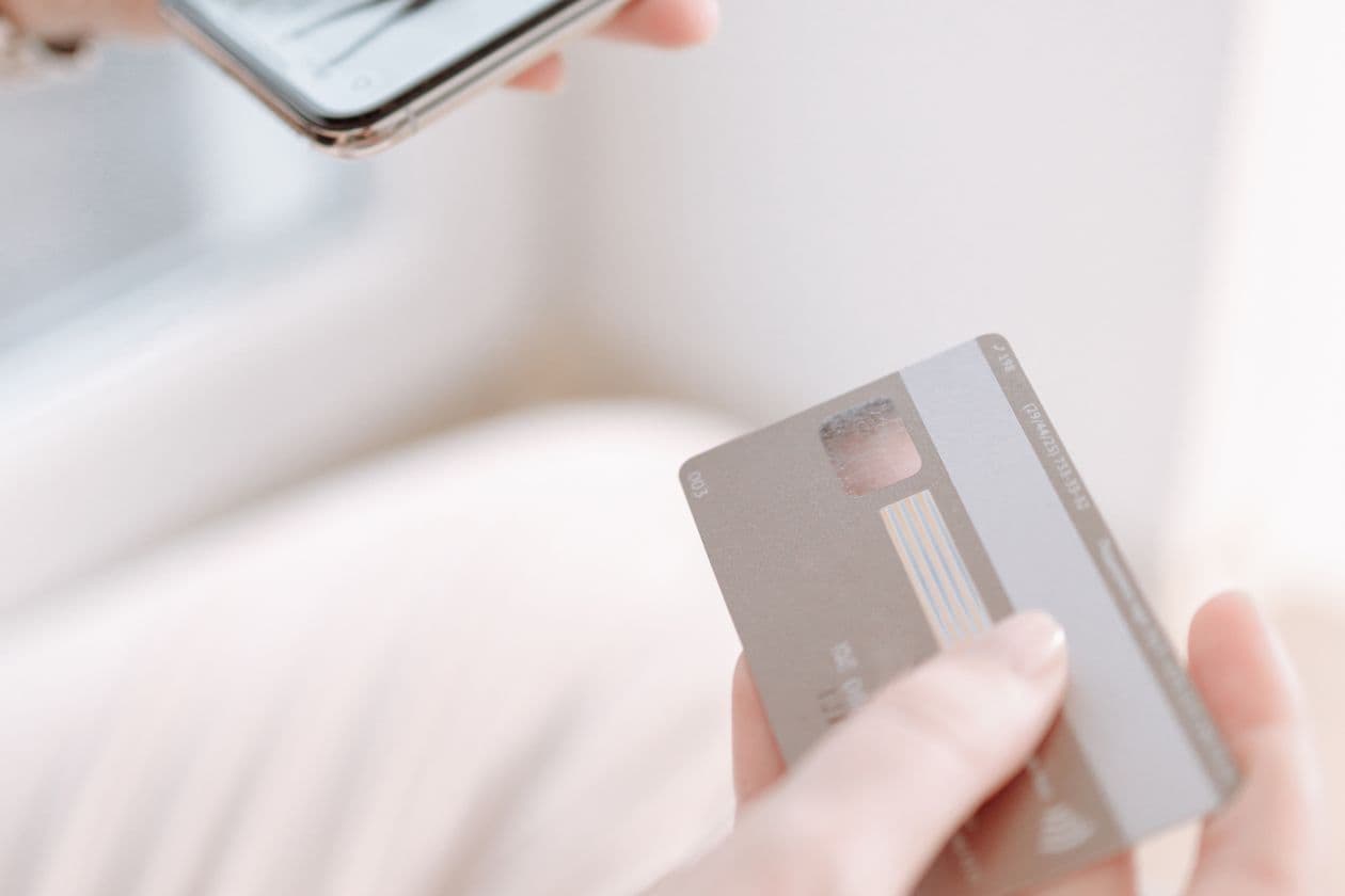 Hands holding a smartphone and a payment card while shopping online
