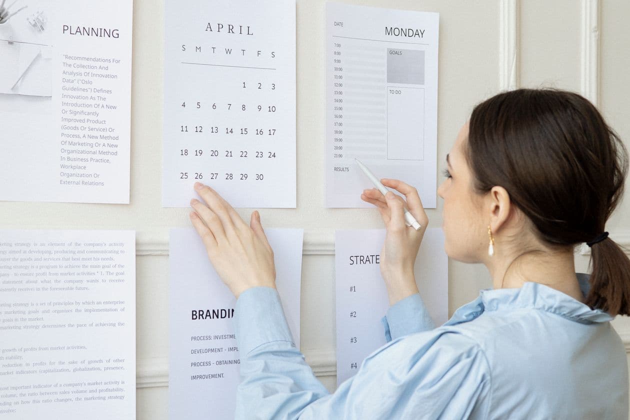 Planner pinning a project schedule and plans to an office wall