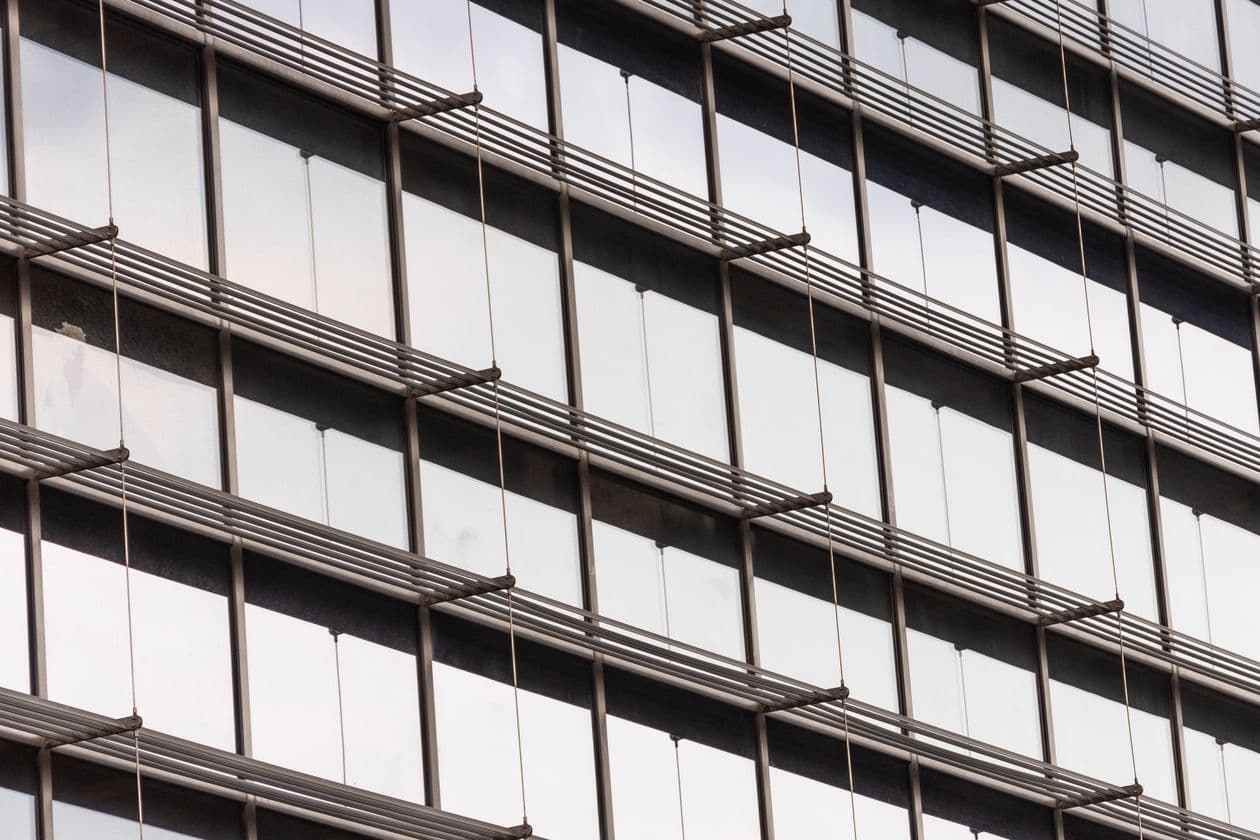 Glass facade of a modern office building with rows of identical windows
