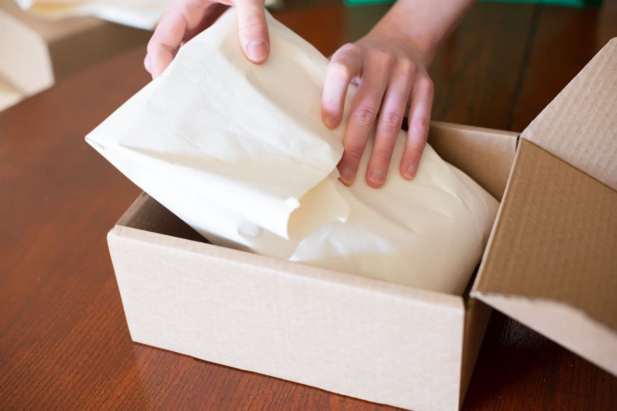 Hands packing a customer order into a cardboard box ready for shipping