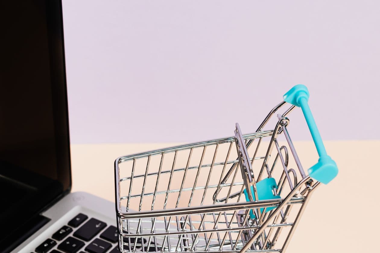 Miniature shopping cart beside a laptop keyboard
