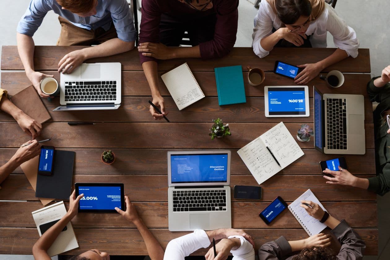 Overhead view of people planning around a table with laptops and notebooks
