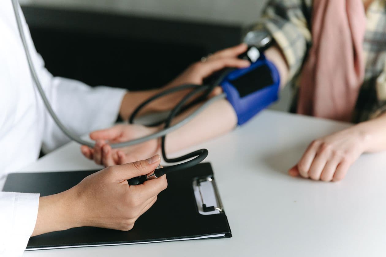 Clinician checking a patient blood pressure at a desk