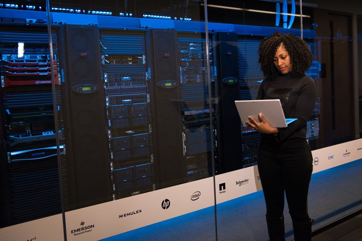 Engineer with a laptop standing beside rows of servers in a data centre