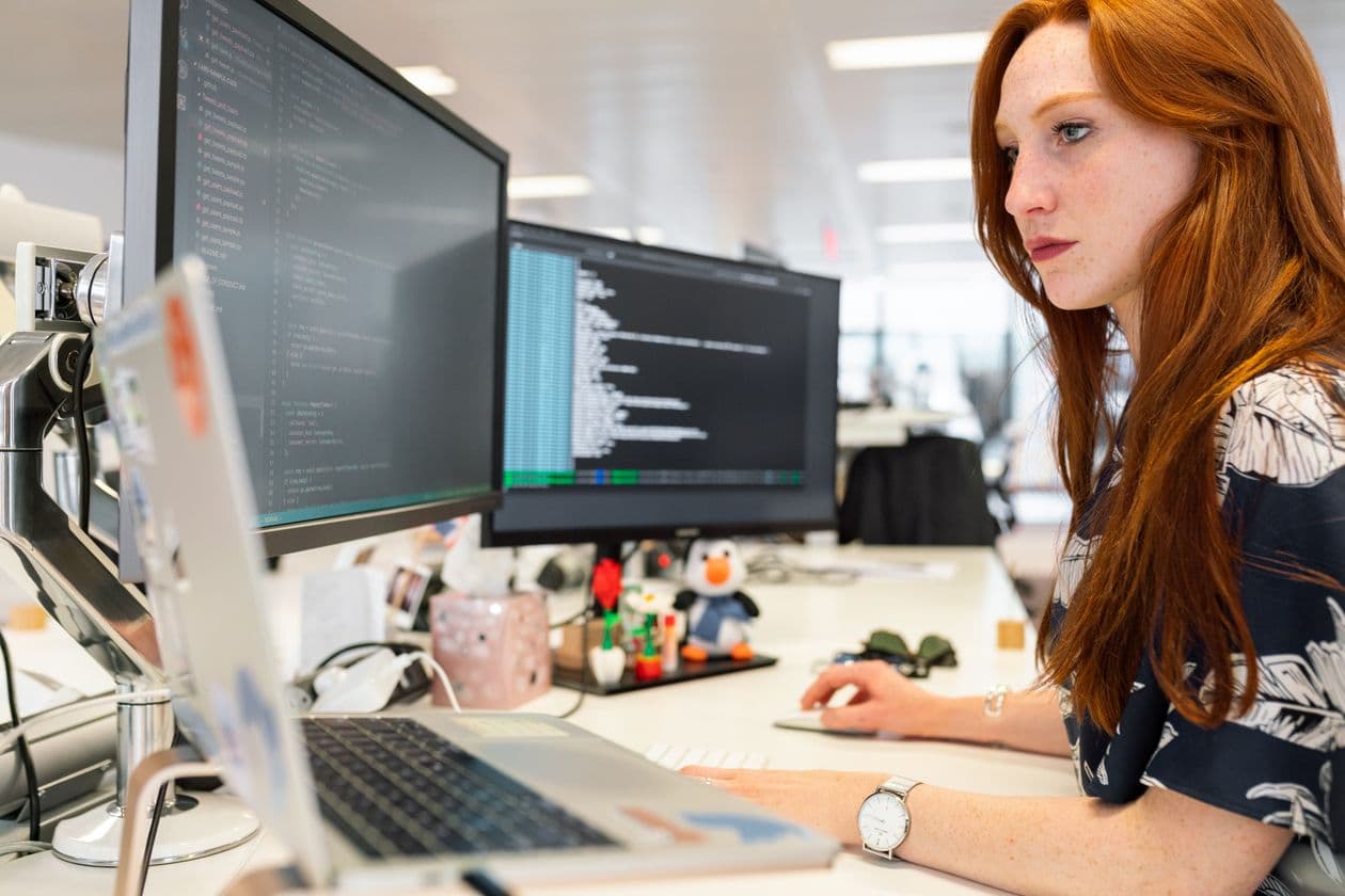 Developer working on code across two large monitors