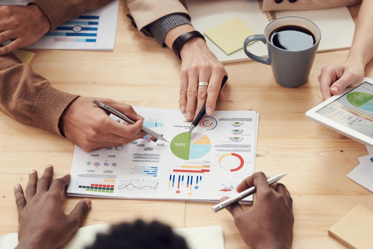 Hands reviewing printed charts and reports on a desk