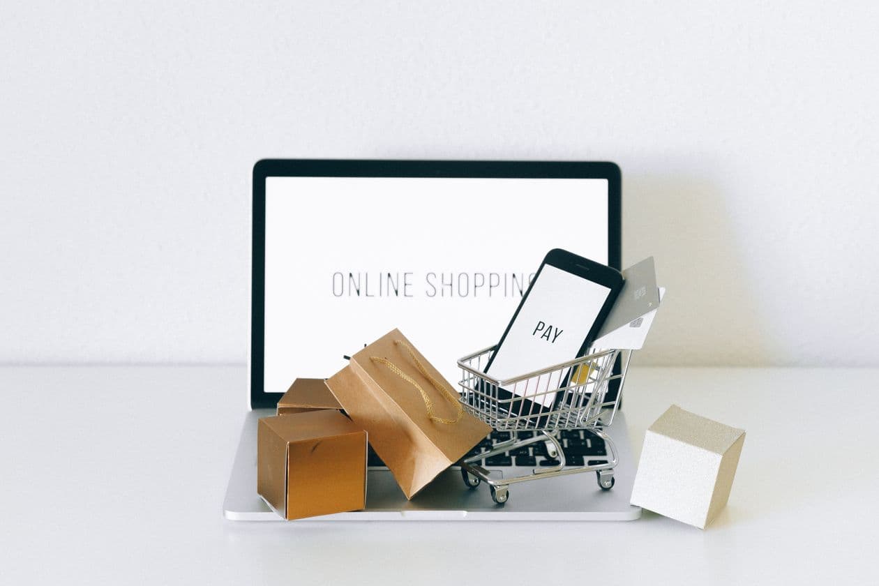 Laptop showing an online shop with parcels and a small shopping cart beside it